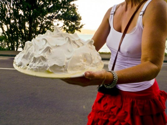 A woman in Karaka Bay carrying a mountainous pavlova across the road.