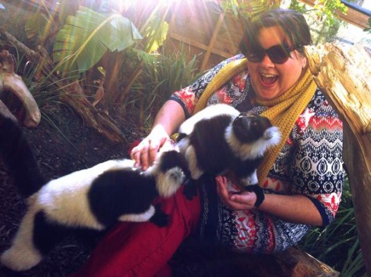 A fat girl is insanely overjoyed at the two fluffy creatures climbing on her lap