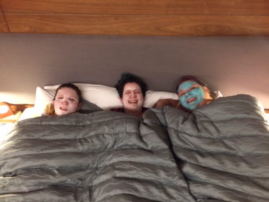 image of three people lying in bed wearing face masks