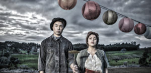 A man and a woman stand next to each other underneath a row of round lanterns.