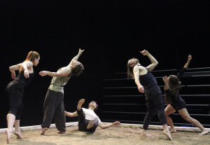 Four dancers are standing while one is on the ground between 