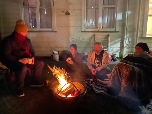 a group of people sitting around an outdoor fire